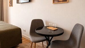 A hotel room with a bed, a TV, a framed picture, a small round table with glasses, and two chairs. - Porto Ribeira Hotel - Superior Double Room (Porto)