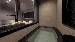 A modern bathroom with a large mirror, a bathtub, and a vanity with a sink.