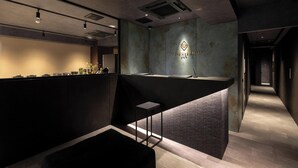 A reception area with a reception desk, a wall-mounted logo, and a staircase leading to another level.