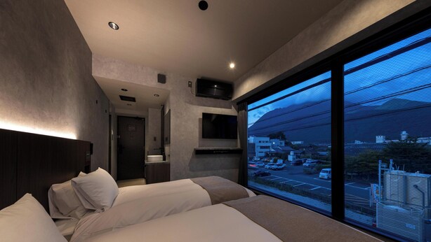 A hotel room with a large bed, a desk, and a view of a cityscape.
