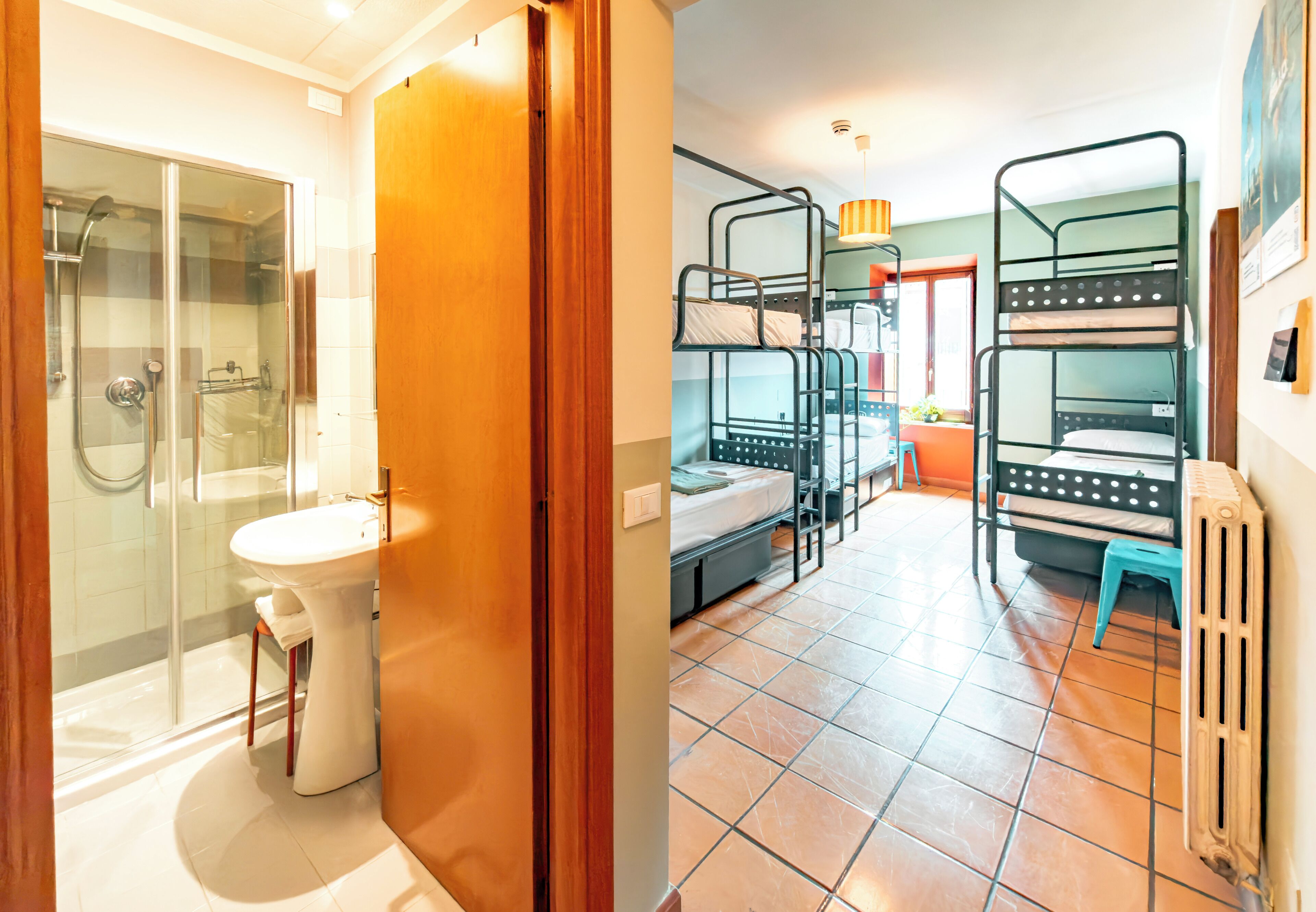 Una habitación de hotel con ducha, lavabo y una cama con literas.