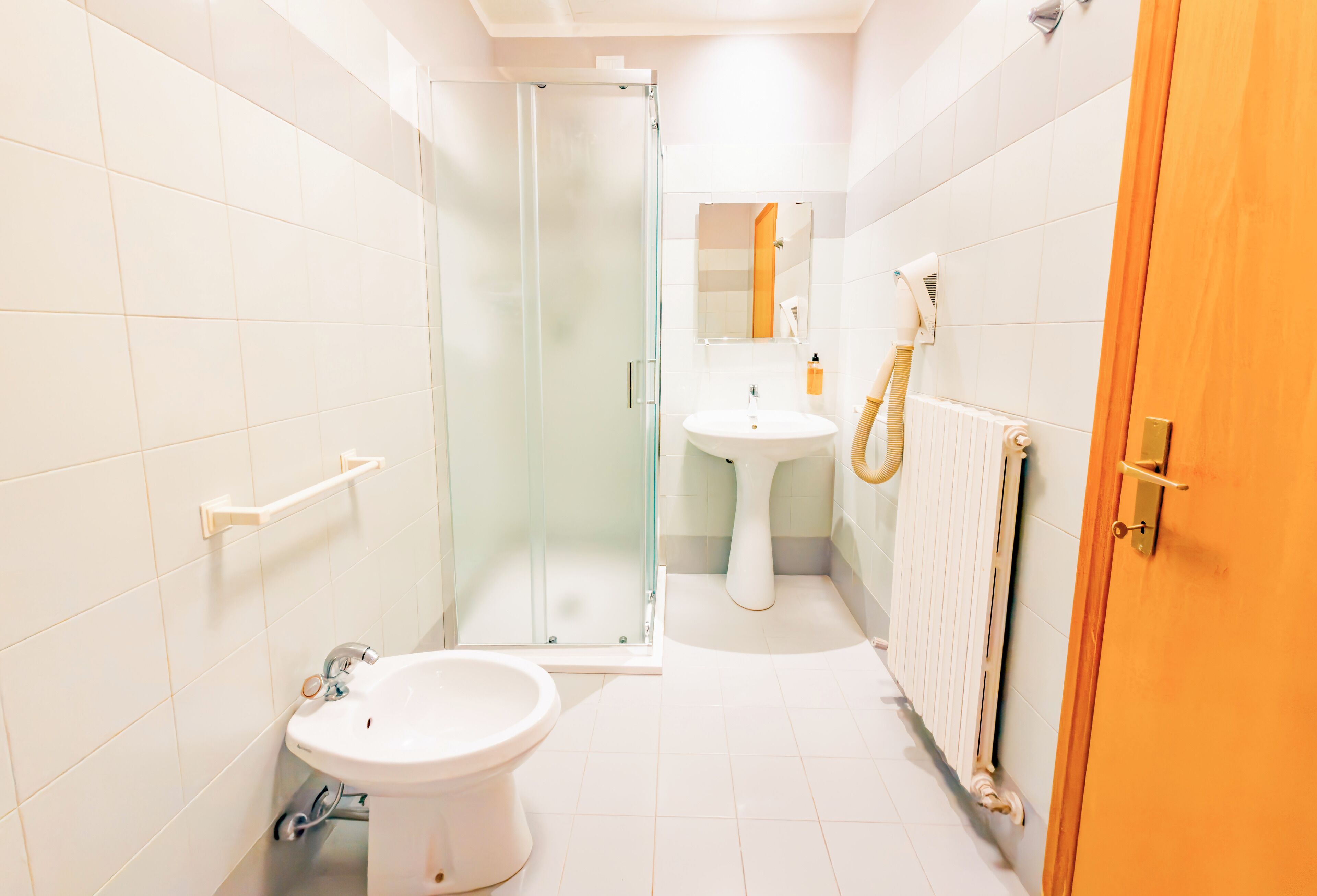 A bathroom with a glass shower enclosure, a white sink, and a toilet.