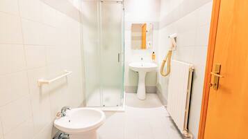 A bathroom with a glass shower enclosure, a white sink, and a toilet.