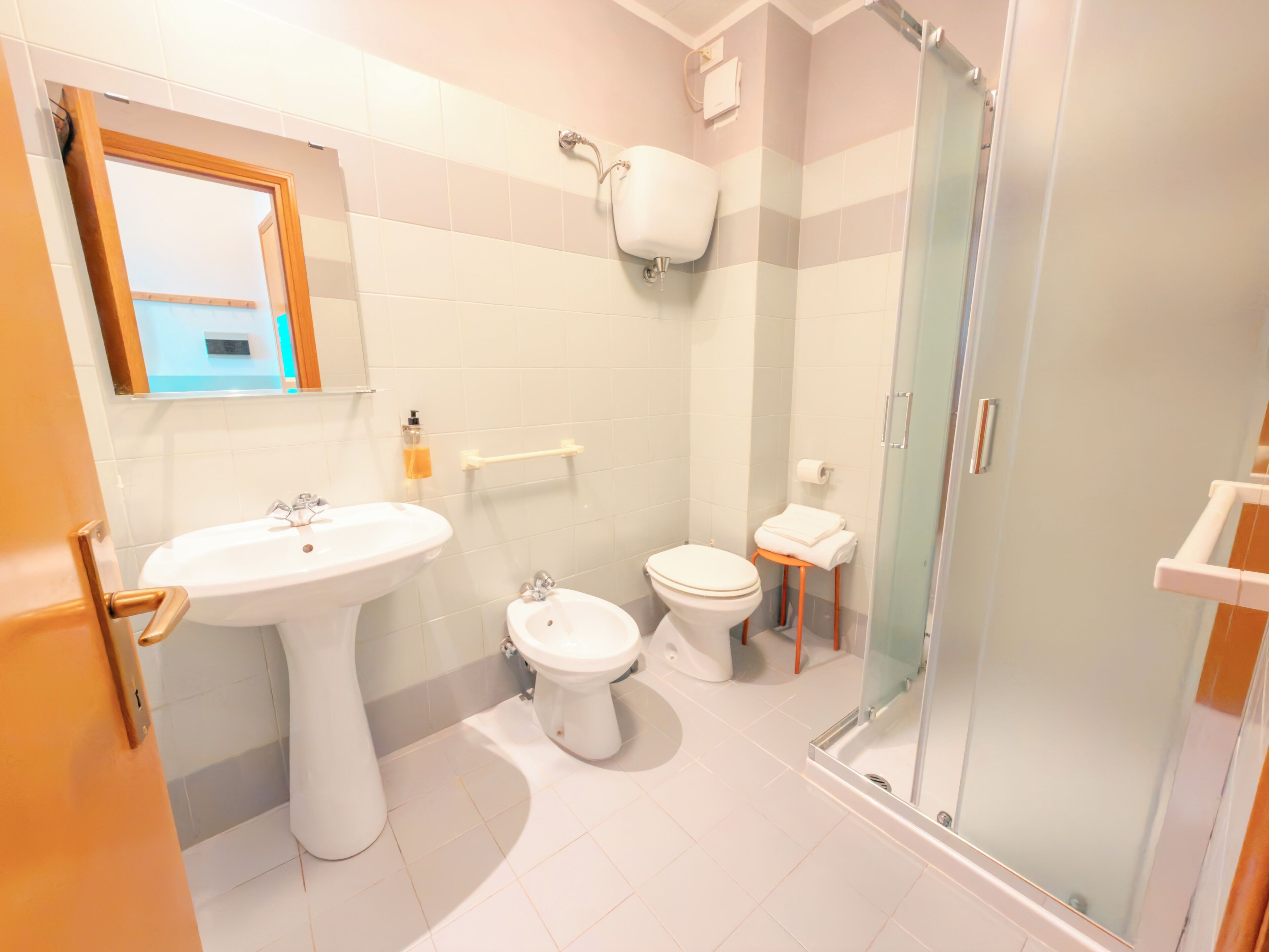 Een badkamer met een wastafel, toilet, bidet en een douchecabine.
