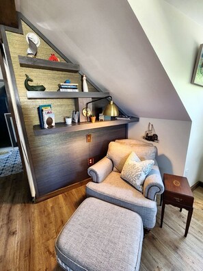 Ein Loft-Zimmer mit integriertem Schreibtisch, einem Sessel, einem kleinen Tisch und einer Treppe.