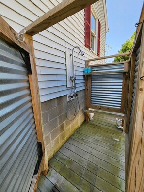 A wooden deck with a metal gate, a hose, and a small shelf with bottles. - Pony Tales | Near Assateague & Wildlife Refuge (Chincoteague Island)