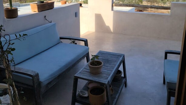 En tagterrasse med sofa, lille bord og plantekasser.