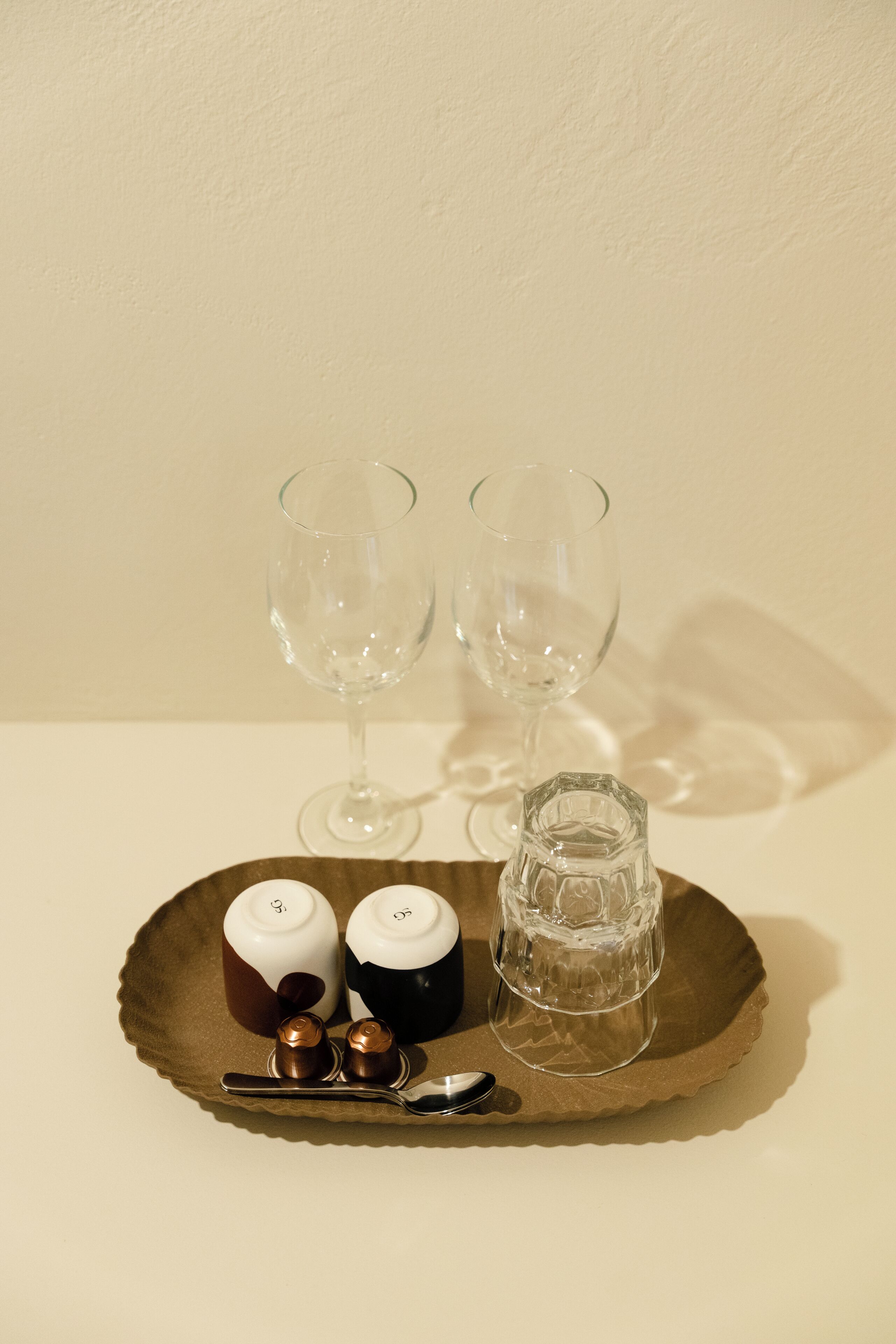 Una bandeja con dos vasos, un juego de salero y pimentero, y un vaso pequeño sobre una mesa.