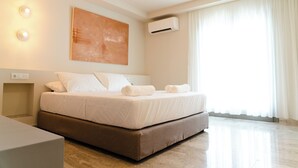 A modern hotel room with a large bed, a bedside table, an air conditioning unit, and a large window with curtains. - Yara (Nafpaktos)