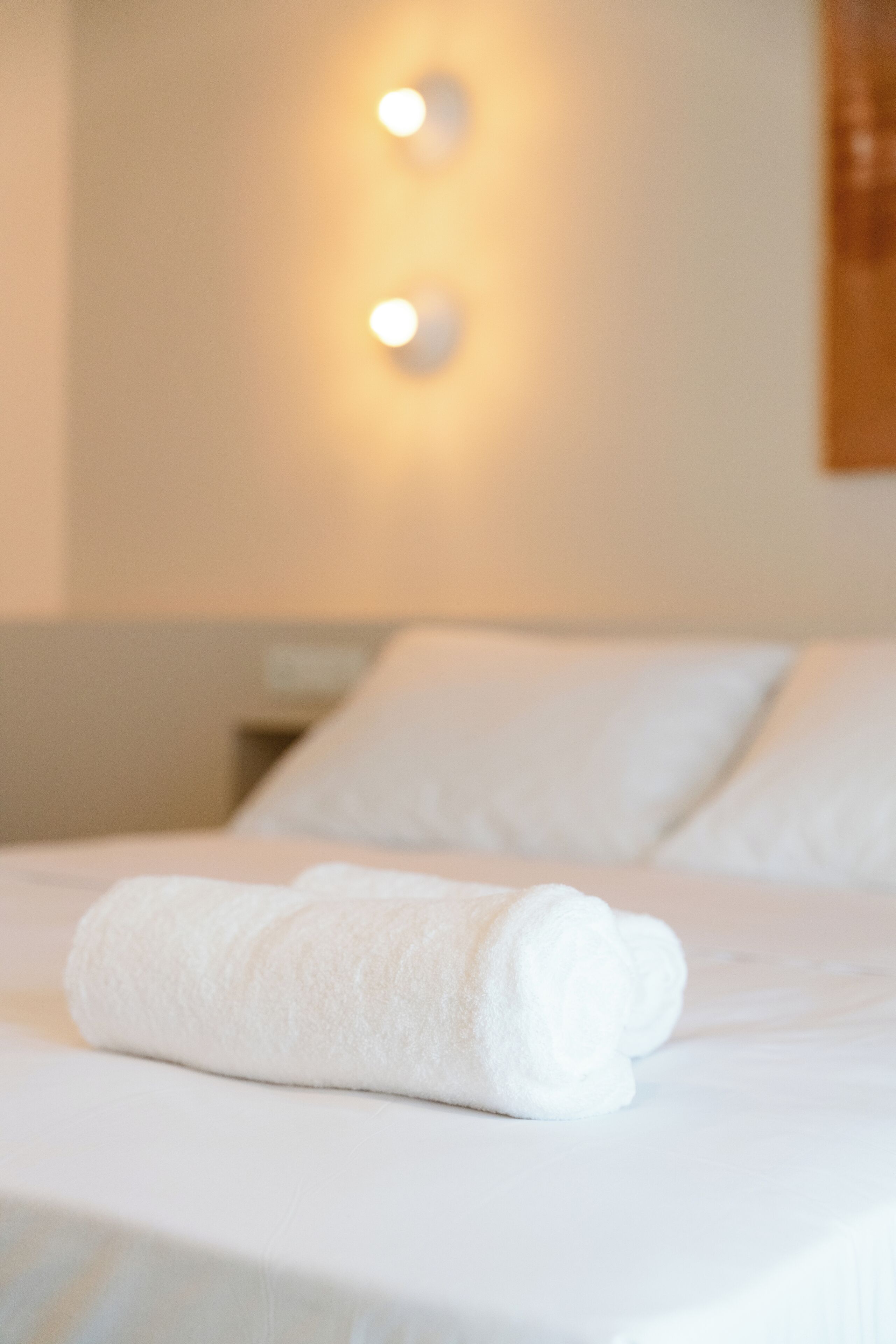 A neatly made bed with a folded white towel on it.