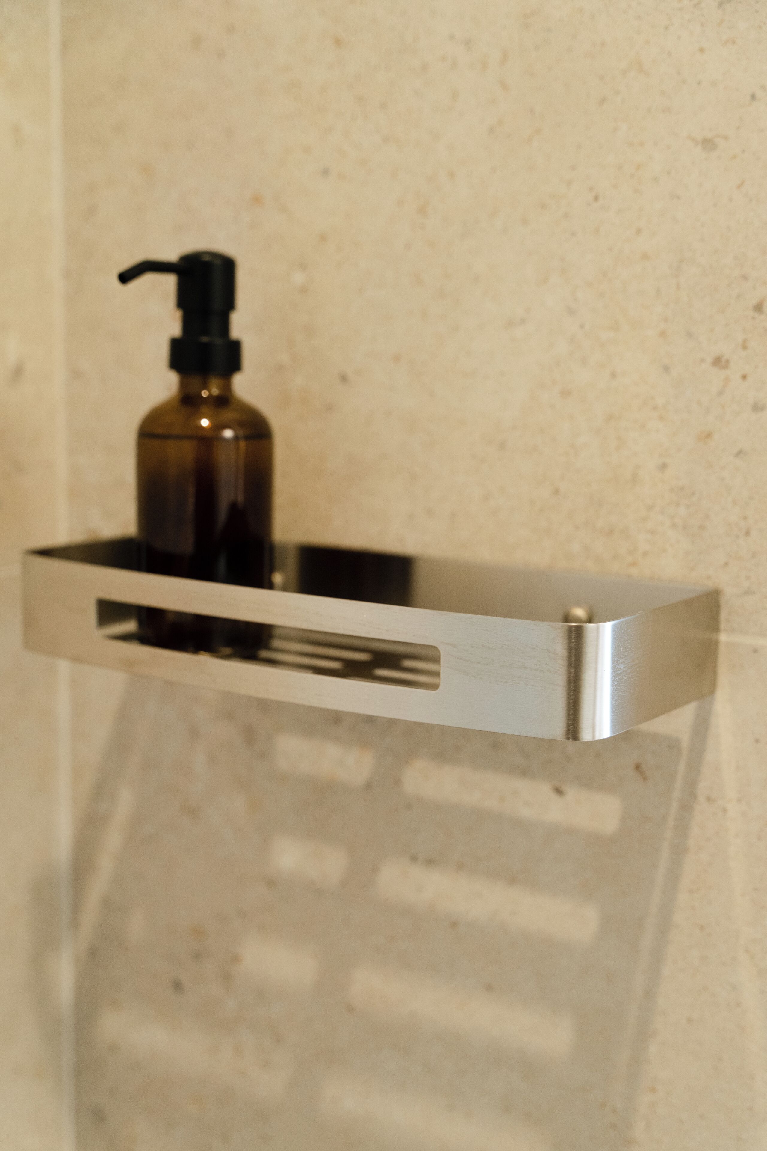 Une salle de bain avec un distributeur de savon en métal fixé au mur.