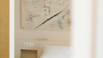 A hotel room with a bed, a nightstand, a power outlet, and a wall-mounted artwork.
