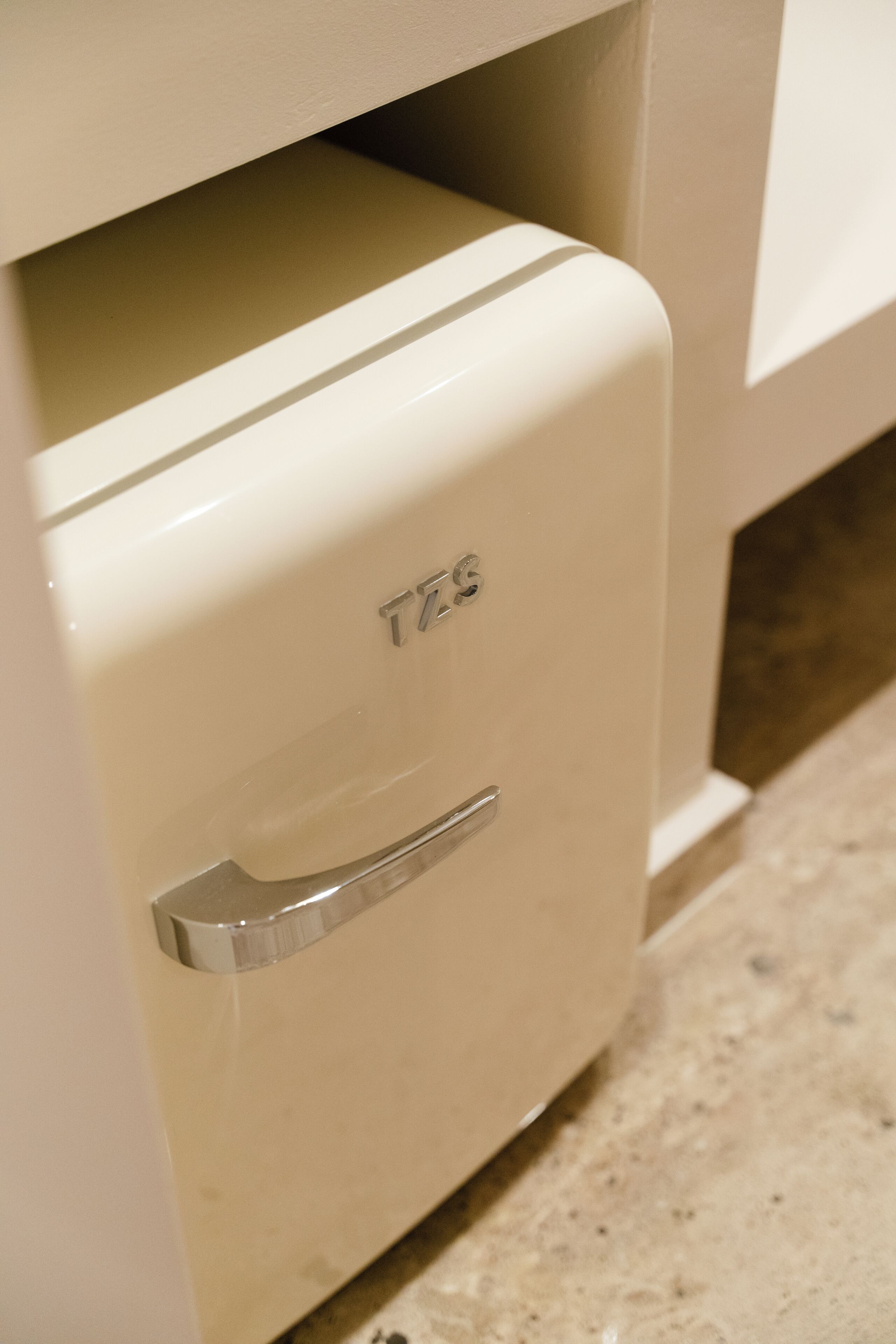 A white cabinet with a handle and the letters 'TZS' on the front.