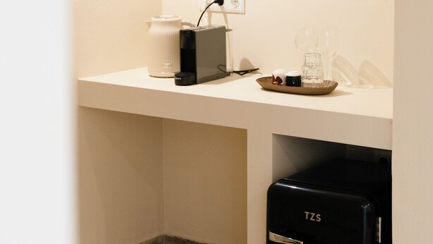 A kitchenette with a coffee maker, a kettle, and a black refrigerator. - Yara (Nafpaktos)