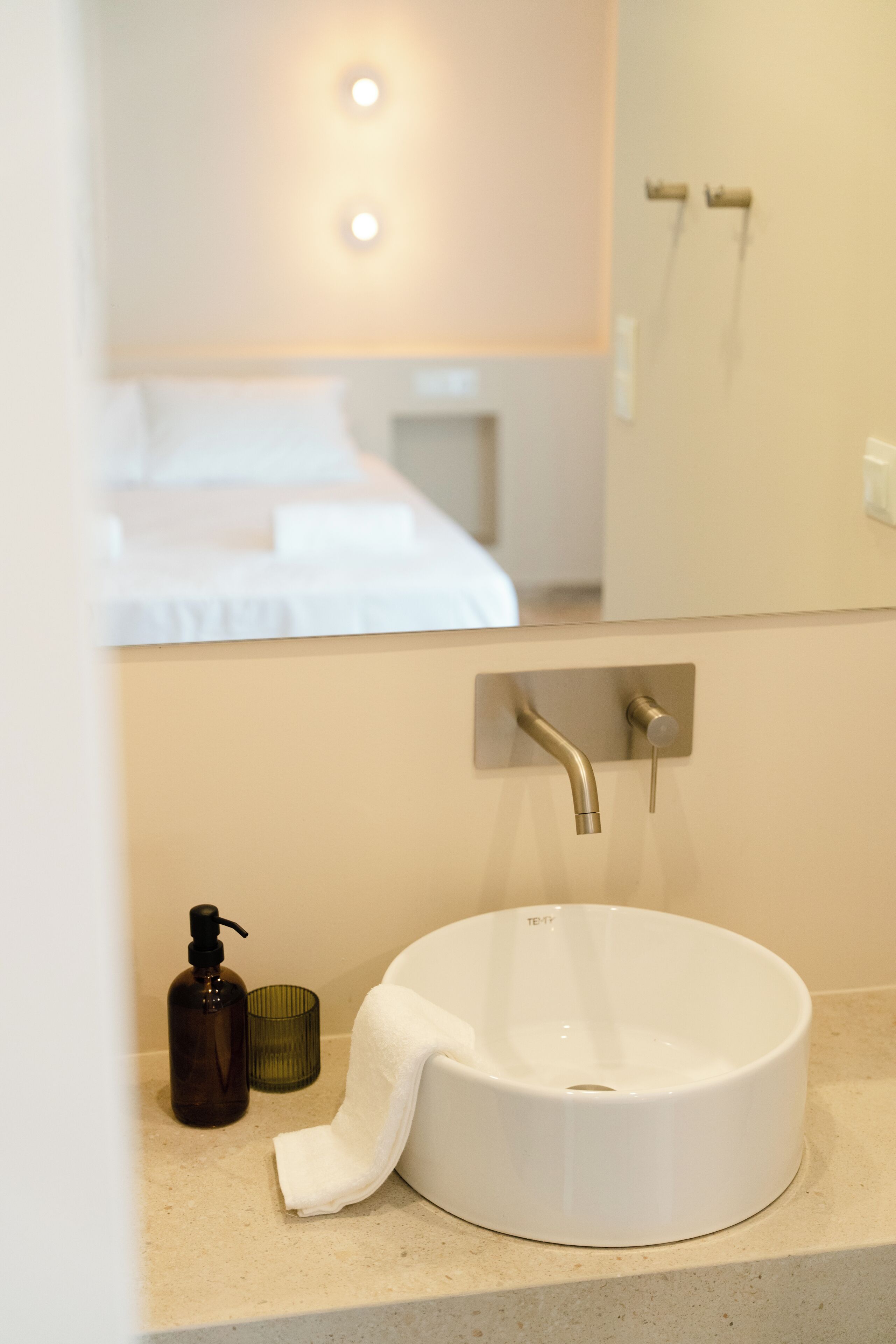A bathroom with a white sink, a bottle of soap, and a towel.