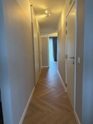 A hallway with wooden flooring, white walls, and doors leading to rooms. - Apartment for 8 people in Koksijde-Bad—just a stone's throw from the beach (Koksijde)