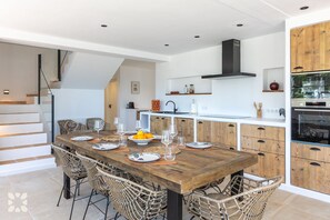 Eine moderne Küche mit einem Holzespeisetisch, Korbstühlen und einem eingebauten Backofen.