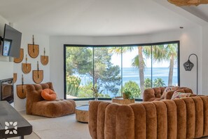 Ein modernes Wohnzimmer mit großem Fenster, einer Couch, einem Couchtisch und Wandgitarrren.