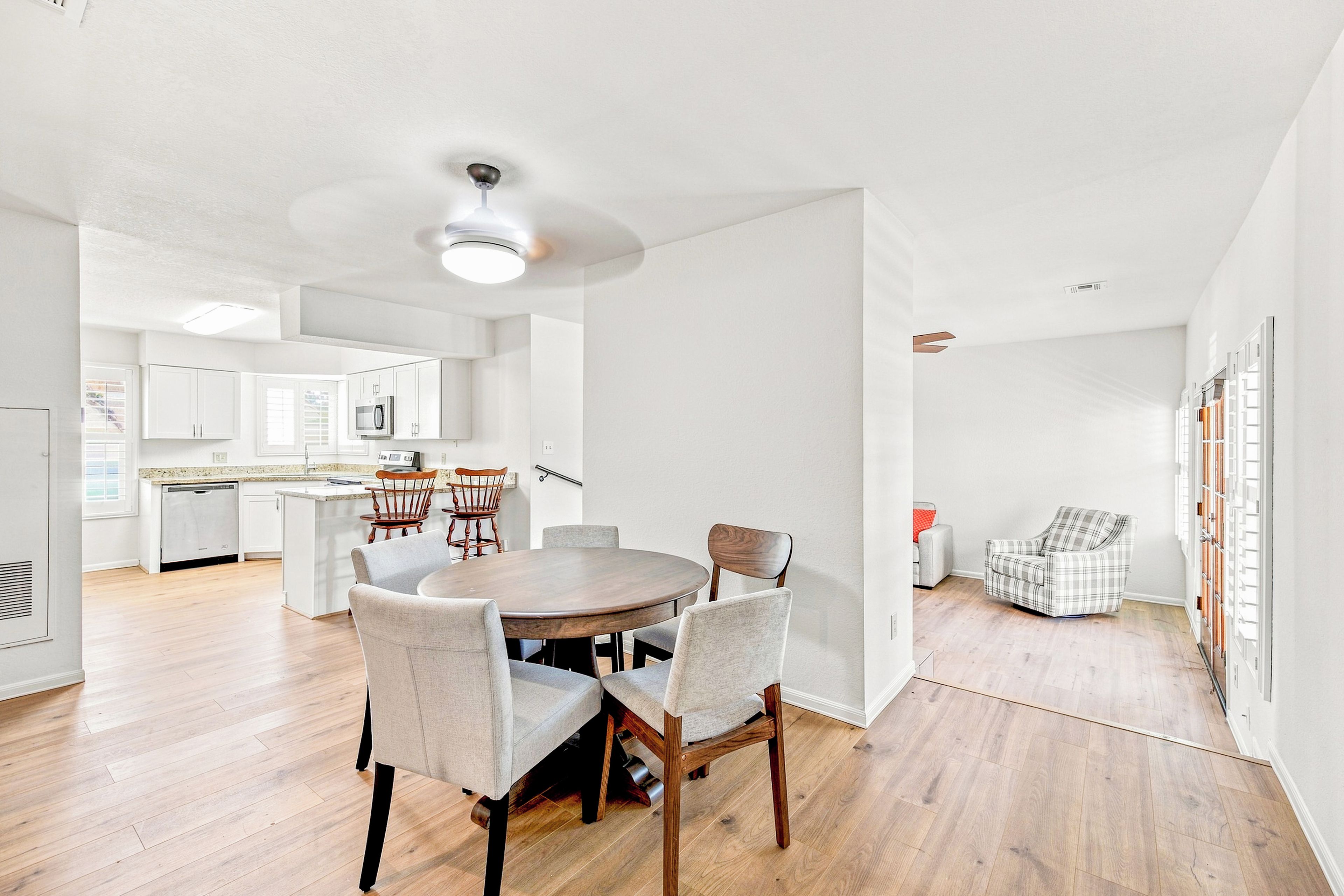 A modern kitchen with white cabinets, a built-in microwave, and a dining area with a round table and chairs.