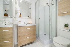 Ein modernes Badezimmer mit Duschkabine aus Glas, einer weißen Toilette und Holzschränken.