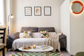 Ein gemütliches Zimmer mit einem Bett, einem runden Tisch mit einer Zeitschrift und einer Lampe.