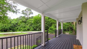 A covered porch with a view of a green landscape and a road. - The Magnolia on 54th (Columbus)