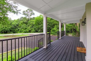 Eine überdachte Veranda mit Blick auf eine grüne Landschaft und eine Straße.