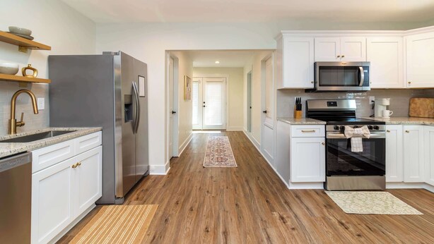 A modern kitchen with white cabinetry, stainless steel appliances, and a wooden floor. - The Magnolia on 54th (Columbus)