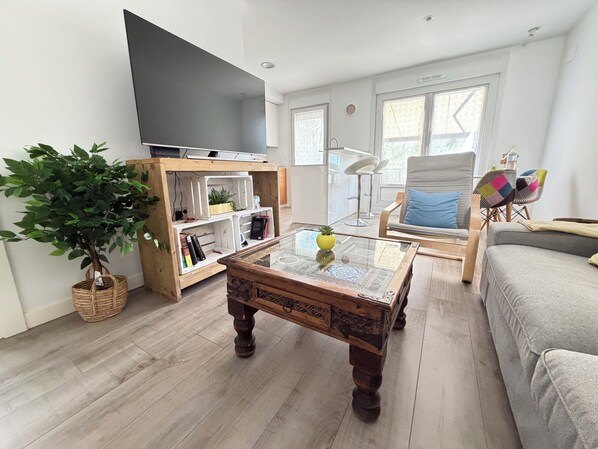 A living room with a television, a coffee table, a sofa, a chair, and a bookshelf.