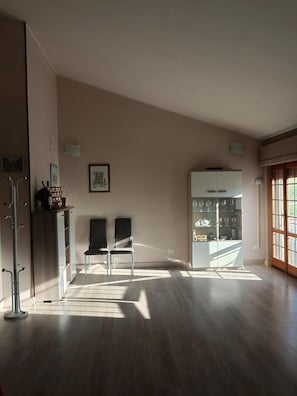 Una habitación amplia con techo alto, un armario empotrado con puertas de cristal, dos sillas y un perchero.