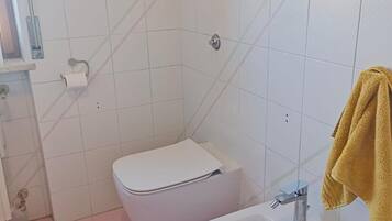 Une salle de bain équipée de toilettes, d’un bidet et d’un lavabo.