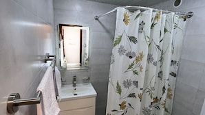 Un baño con cortina de ducha, lavabo, espejo y retrete.