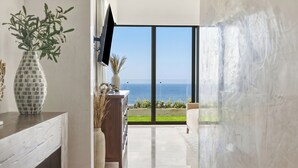 Ein modernes Interieur mit großem Fenster zum Meer, einem wandmontierten Flachbildfernseher und einem minimalistischen Design.