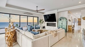 Ein modernes Wohnzimmer mit einer großen Couch, einem Flachbildfernseher und Blick auf den Ozean.