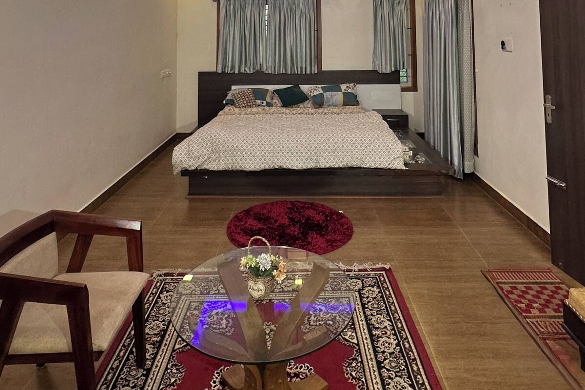 Un dormitorio moderno con cama, ventilador de techo, unidad de aire acondicionado y una mesita con un florero.