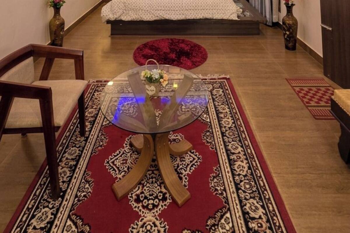 Habitación de hotel con cama, zona de estar con una mesa, ventilador de techo y aire acondicionado de pared.