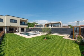 Ein modernes, zweistöckiges Haus mit Swimmingpool, einem eingezäunten Garten und einem kleinen Gemüsegarten.