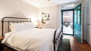 Une chambre à coucher comprenant un lit, un ventilateur de plafond, une bibliothèque et une porte donnant sur un espace extérieur.