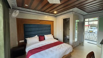 A bedroom with a wooden headboard, a bed with white and red bedding, a nightstand, and a door leading to a balcony.