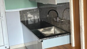 Eine Küche mit schwarzer Arbeitsplatte, Edelstahl-Spüle und weißen Schränken.