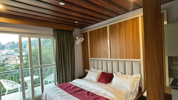Ein Schlafzimmer mit einem großen Bett, einem Balkon mit weißen Stühlen und Blick auf die Stadt.