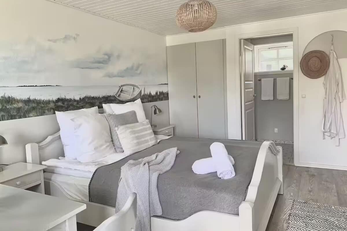 Une chambre à coucher comprenant un lit, des tables de chevet, un luminaire suspendu, une armoire et une vue sur la mer.