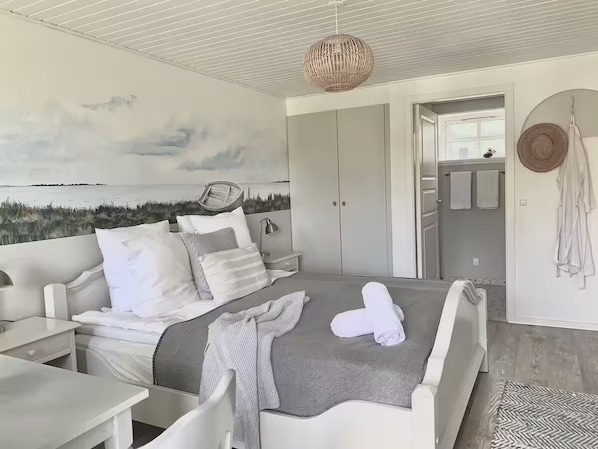 Une chambre à coucher comprenant un lit, des tables de chevet, un luminaire suspendu, une armoire et une vue sur la mer.