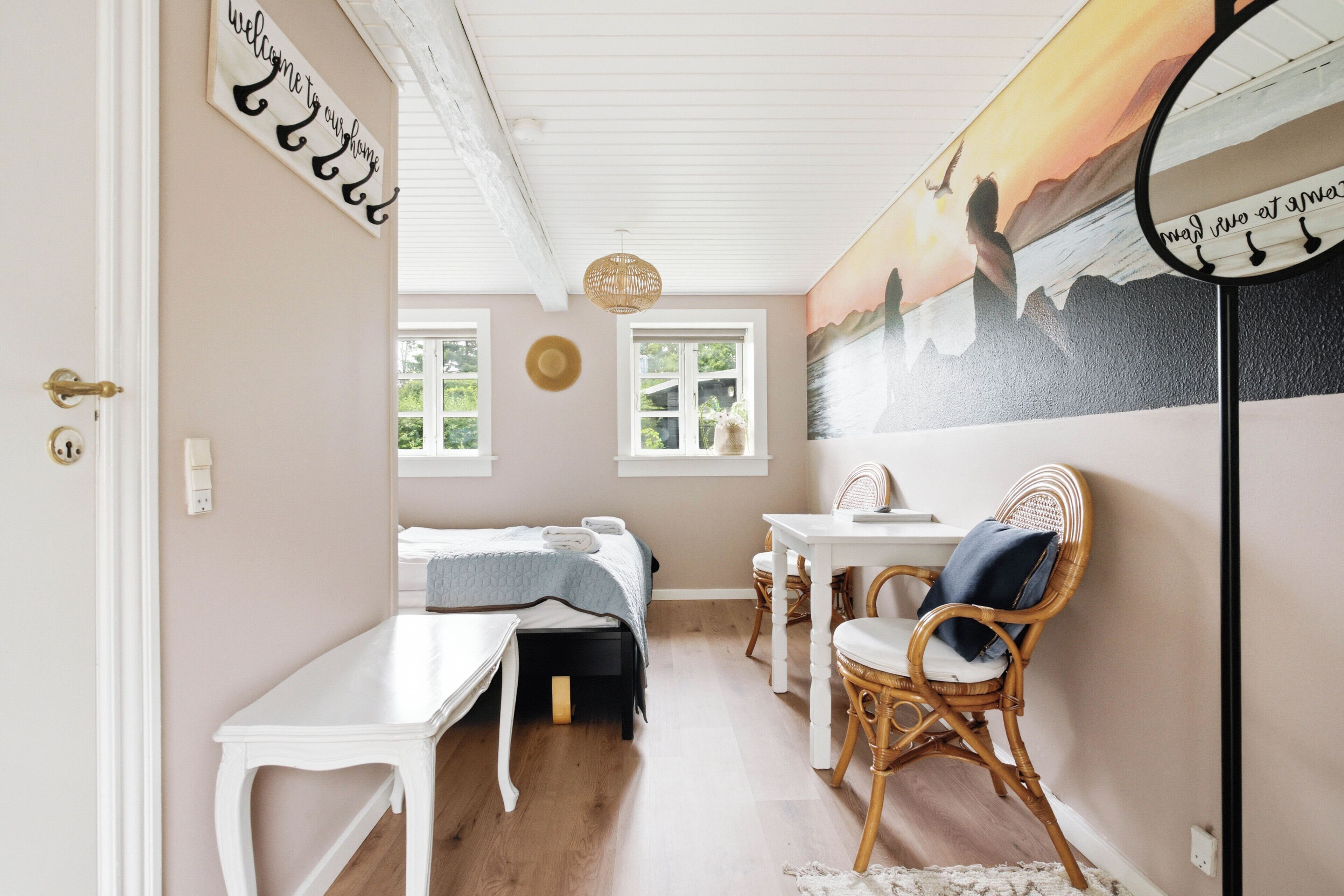 A bedroom with a bed, a desk, a chair, a wall-mounted mirror, and a window.