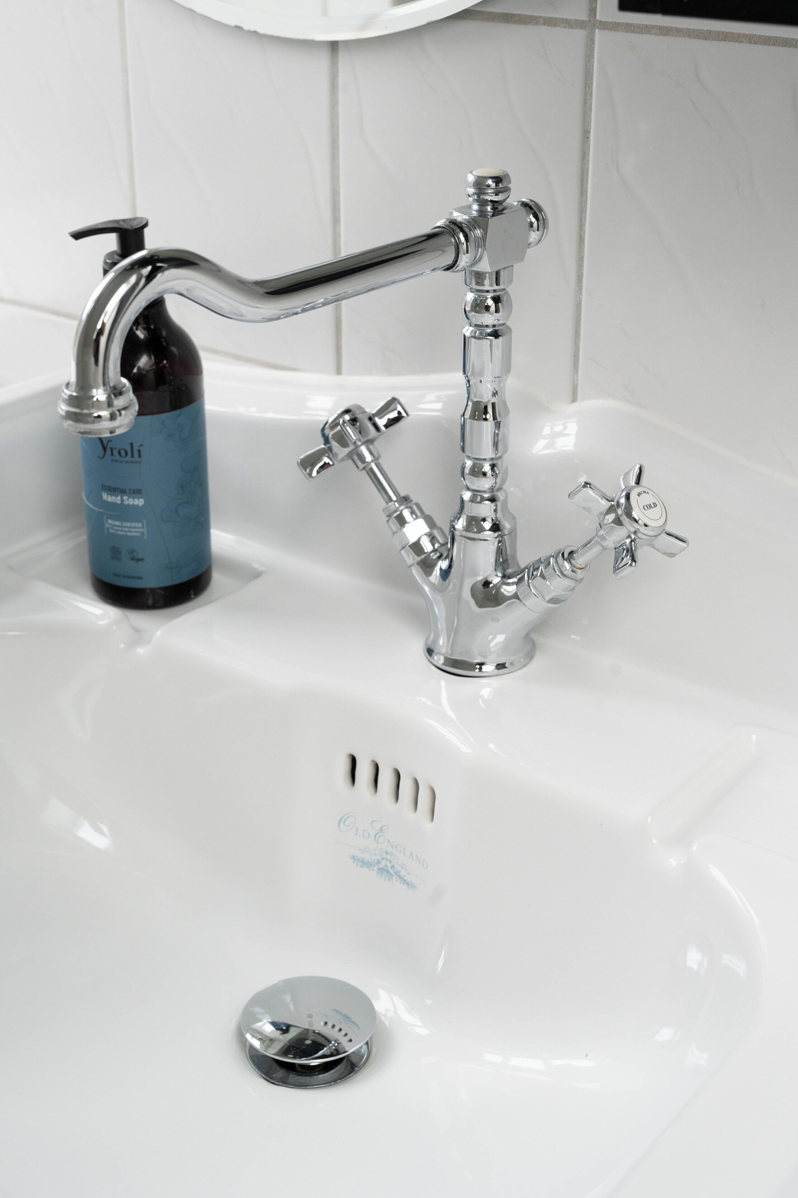 A bathroom sink with a chrome faucet, a soap dispenser, and a drain cover.