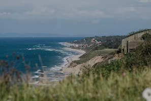 Un paysage côtier avec une plage, une clôture en bois et des bâtiments en arrière-plan.