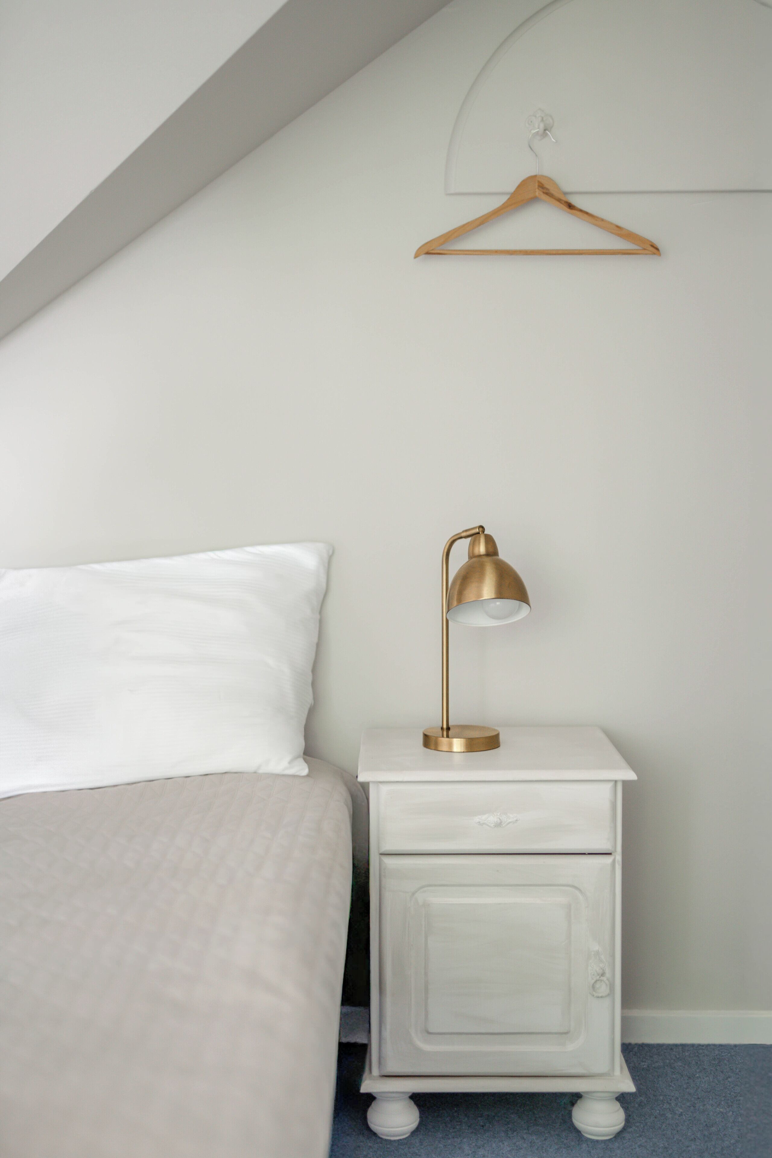 Una camera da letto con un letto, un comodino con una lampada, un lampadario e un armadio.
