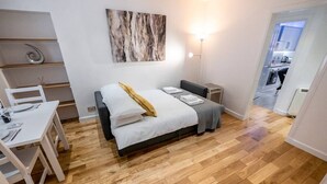 Quarto com cama, mesas de cabeceira, escrivaninha e uma cadeira.