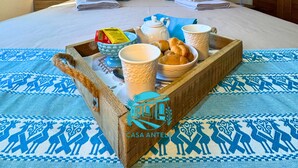 Quarto de hotel com cama, abajures, bandeja com itens de café da manhã e tapete estampado.