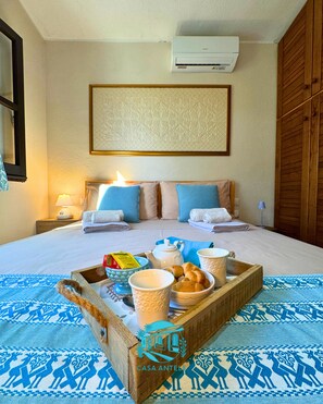 A hotel room with a bed, bedside lamps, a tray with breakfast items, and a patterned rug. - Casa Antele, a relaxing retreat nestled between the garden and the sea in southern Sardinia  (Quartu Sant'Elena)
